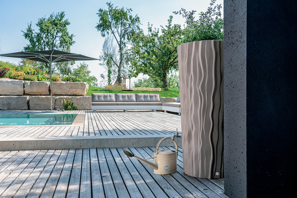 Moderne Außendusche auf einem Holzdeck neben einem Pool mit Liegebereich im Hintergrund, inklusive Regenwassernutzung aus einer YourCasa Regentonne 160 Liter [AquaDesign Flower] - Frostsicher & UV-beständig von yourcisade.com.