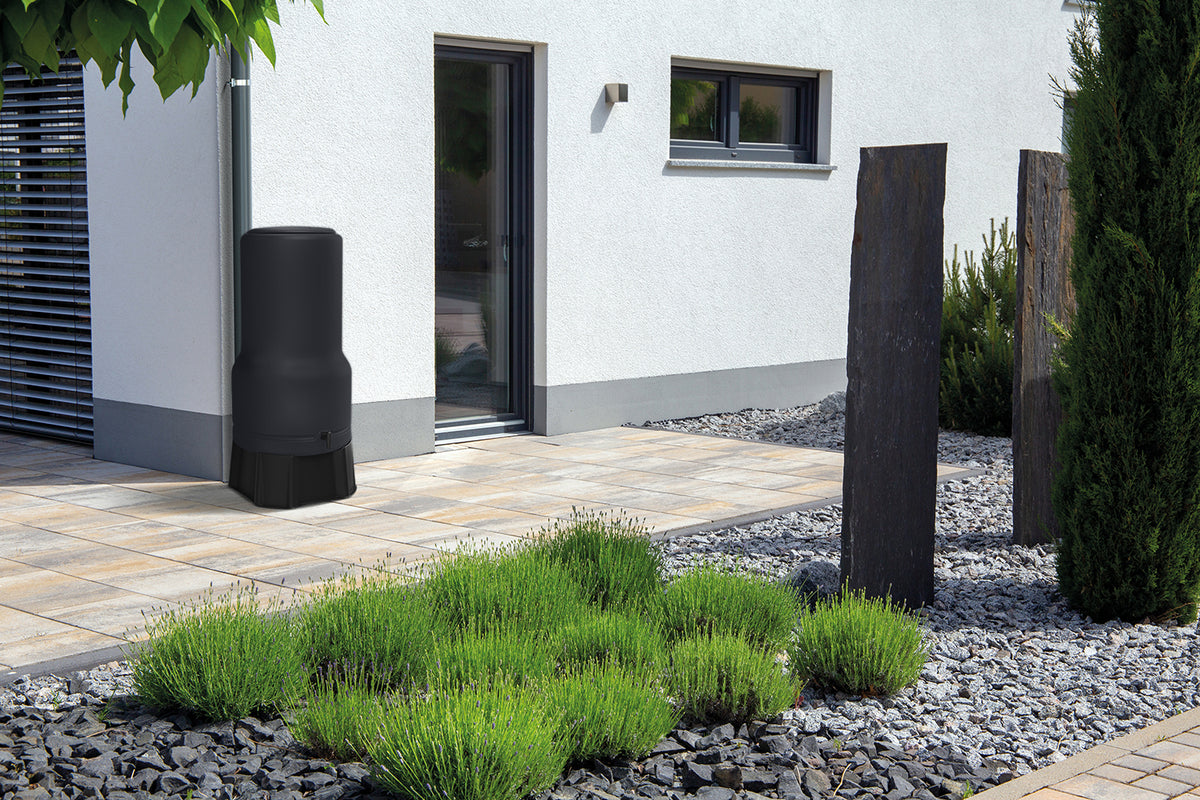 Modernes Hausäußeres mit gepflegter Gartenanlage und einer Regenwassersammeltonne mit YourCasa Regentonne [RainBell] mit Standfuß, Deckel und Wasserhahn von yourcisade.com.